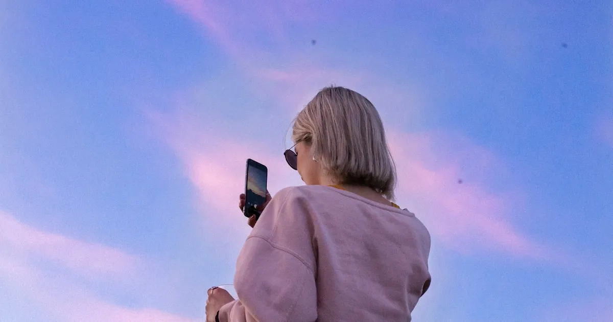 woman in sunglasses and pink top holding phone