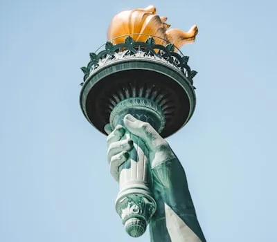 a statue of a hand holding a golden pig on top of a statue of liberty