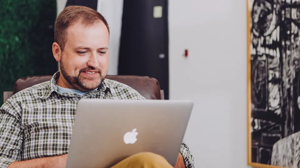 man smiling and using MacBook