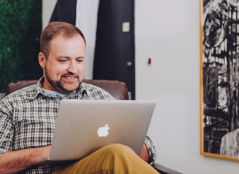 man smiling and using MacBook