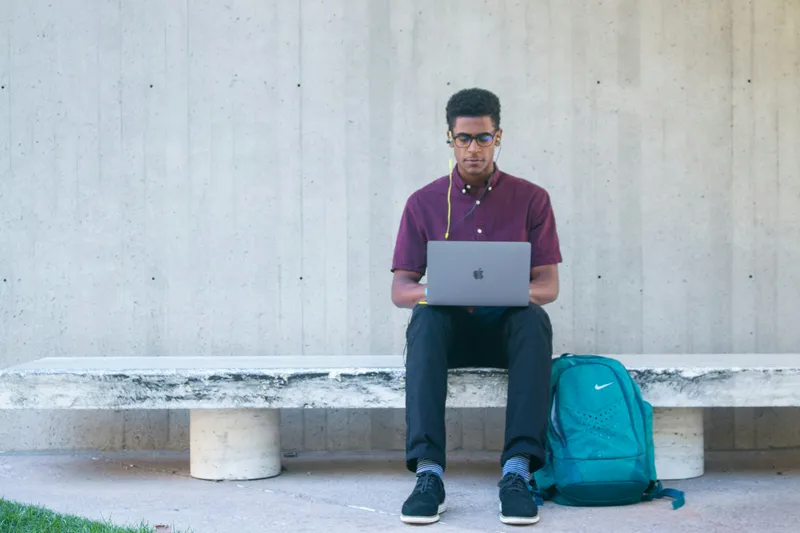 a man sitting on a bench with a laptop