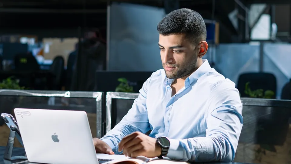 A man sitting at a table using a laptop computer