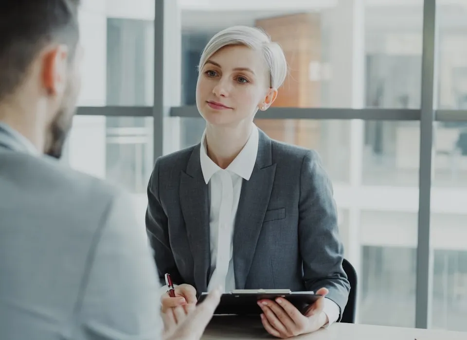 Woman in suit interviews man at desk